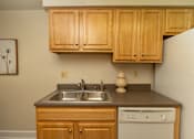 Thumbnail 12 of 36 - A kitchen with wooden cabinets and a white refrigerator.at Chapel Valley Townhomes, Maryland, 21236