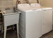 Thumbnail 15 of 15 - A white washing machine and sink in a laundry room at Kingston Townhomes, Baltimore, MD