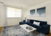 Thumbnail 5 of 19 - a living room with a blue couch and a coffee table at Winston Apartments, Baltimore, MD