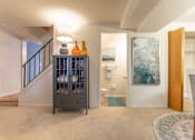 Thumbnail 8 of 31 - A grey cabinet with bottles on top is in a room with a rug and a painting on the wall.