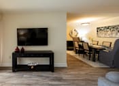 Thumbnail 9 of 28 - A black coffee table with a TV above it and a red vase on it.