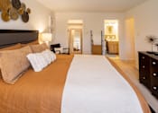 Thumbnail 13 of 21 - A bedroom with a large bed and a mirror on the wall.