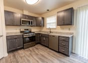 Thumbnail 2 of 22 - a kitchen with dark wood cabinets and stainless steel appliances at Carlson Woods Townhomes, Maryland, 21244