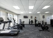 Thumbnail 17 of 19 - A spacious gym with treadmills, exercise bikes, and other equipment.