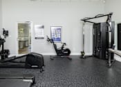 Thumbnail 27 of 32 - A gym with a treadmill, elliptical trainer, stationary bike and a rowing machine.