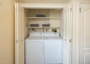 Thumbnail 11 of 25 - Full-sized washer and dryer with shelving with baskets behind closet doors at Ivy Hall Apartments*, Maryland, 21204