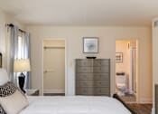 Thumbnail 19 of 25 - Bedroom with a bed looking into walk-in closet and ensuite bathroom at Ivy Hall Apartments*, Towson, MD 21204.