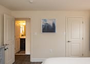 Thumbnail 12 of 16 - A bedroom with a bed, a painting, and a door.