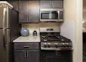 Thumbnail 3 of 16 - Kitchen with black cabinets, granite countertops, microwave, and gas stovetop.