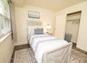 Thumbnail 12 of 25 - Second bedroom with bed, nightstand with mirror, and closet at Village of Pine Run Apartments & Townhomes*, Maryland, 21244