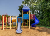Thumbnail 27 of 32 - Playground with a blue and red swing set and a yellow and red slide at Seven Oaks Townhomes, Edgewood