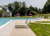 Thumbnail 18 of 32 - Swimming pool with lounge chairs and umbrellas at Seven Oaks Townhomes, Edgewood, Maryland