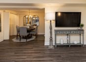 Thumbnail 5 of 32 - A living room with a television, a table, and chairs at Spring Hill Apartments & Townhomes, Baltimore, MD 21234.