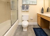 Thumbnail 23 of 32 - A white toilet sits in a bathroom next to a bathtub.