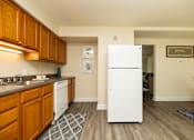 Thumbnail 10 of 22 - A kitchen with a white fridge and wooden cabinets.