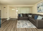 Thumbnail 2 of 22 - A living room with a brown couch and a blue rug.