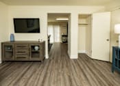 Thumbnail 4 of 22 - A living room with a tv on the wall and a cabinet with glass doors.