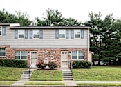 Thumbnail 22 of 22 - A two-story house with a brick facade and a grey siding.