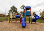 Thumbnail 13 of 15 - a playground with a blue slide and a red slide at Lawyers Hill Apartments, Elkridge, MD
