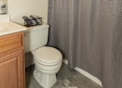 Thumbnail 13 of 36 - A white toilet in a bathroom with a grey shower curtain