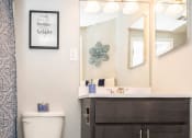 Thumbnail 9 of 24 - a bathroom with a white toilet next to a sink with a mirror above it at Fairbrook Park, Baltimore Maryland