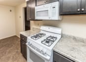 Thumbnail 2 of 22 - A kitchen with a stove and microwave at Foxridge Townhomes, Baltimore, MD