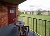 Thumbnail 18 of 23 - Balcony with two chairs and a table at Rockdale Gardens Apartments*, Baltimore, MD