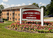 Thumbnail 1 of 16 - A sign for Lawyers Hill Apartments in front of a building.