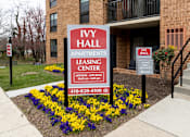 Thumbnail 28 of 28 - A sign for Ivy Hall Apartments leasing center in front of a brick building.