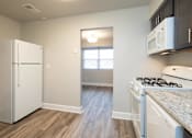 Thumbnail 7 of 25 - Kitchen with a white refrigerator freezer next to a stove top oven at McDonogh Village Apartments & Townhomes, Randallstown, Maryland, 21133