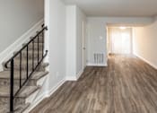 Thumbnail 6 of 25 - A living room with hardwood floors and a staircase at McDonogh Village Apartments & Townhomes, Randallstown