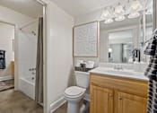 Thumbnail 11 of 19 - A bathroom with a toilet, sink, and shower at Woodsdale Apartments in Abingdon, MD