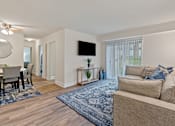 Thumbnail 3 of 19 - A living room with a couch, a chair, a table, a television, and a rug at Woodsdale Apartments in Abingdon, MD