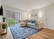 Thumbnail 2 of 19 - A living room with a couch, a rug, and a television at Woodsdale Apartments in Abingdon, MD