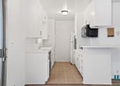 Thumbnail 11 of 23 - A kitchen with white cabinets and appliances.