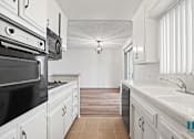 Thumbnail 9 of 23 - A kitchen with white cabinets and a black stove top oven.