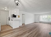Thumbnail 6 of 23 - A spacious living room with wooden flooring and white walls.