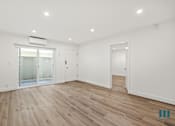 Thumbnail 15 of 23 - A spacious room with wooden flooring and white walls.
