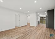 Thumbnail 17 of 23 - A spacious room with wooden flooring and white walls.