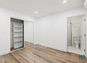 Thumbnail 16 of 23 - A white room with a wooden floor and a refrigerator in the corner.