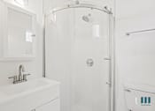 Thumbnail 23 of 23 - A white bathroom with a sink, shower, and toilet.