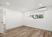 Thumbnail 19 of 23 - A room with wooden flooring and a window showing an outdoor tree.