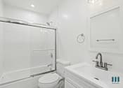 Thumbnail 18 of 23 - A white bathroom with a toilet, sink, and shower.