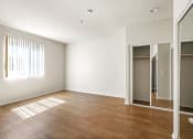 Thumbnail 22 of 38 - Spacious Bedroom with Mirrored Closet, Window, and Vinyl Flooring