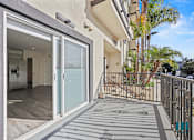 Thumbnail 29 of 48 - A balcony with a glass door leading to a kitchen.
