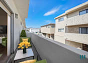 Thumbnail 4 of 39 - A balcony with a table and chairs overlooks a row of buildings.