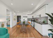 Thumbnail 6 of 49 - A modern kitchen with a green couch and a wooden table.