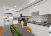 Thumbnail 4 of 49 - A modern kitchen with a long table and chairs.