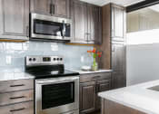 Thumbnail 27 of 31 - a modern kitchen with stainless steel appliances and wooden cabinets