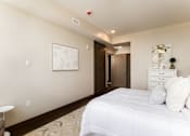 Thumbnail 20 of 33 - A bedroom with a white bed and a painting on the wall.
